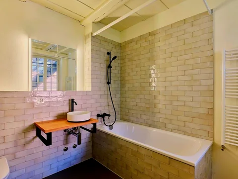 Badezimmer mit Rundbecken auf Holzregal und Spiegel.