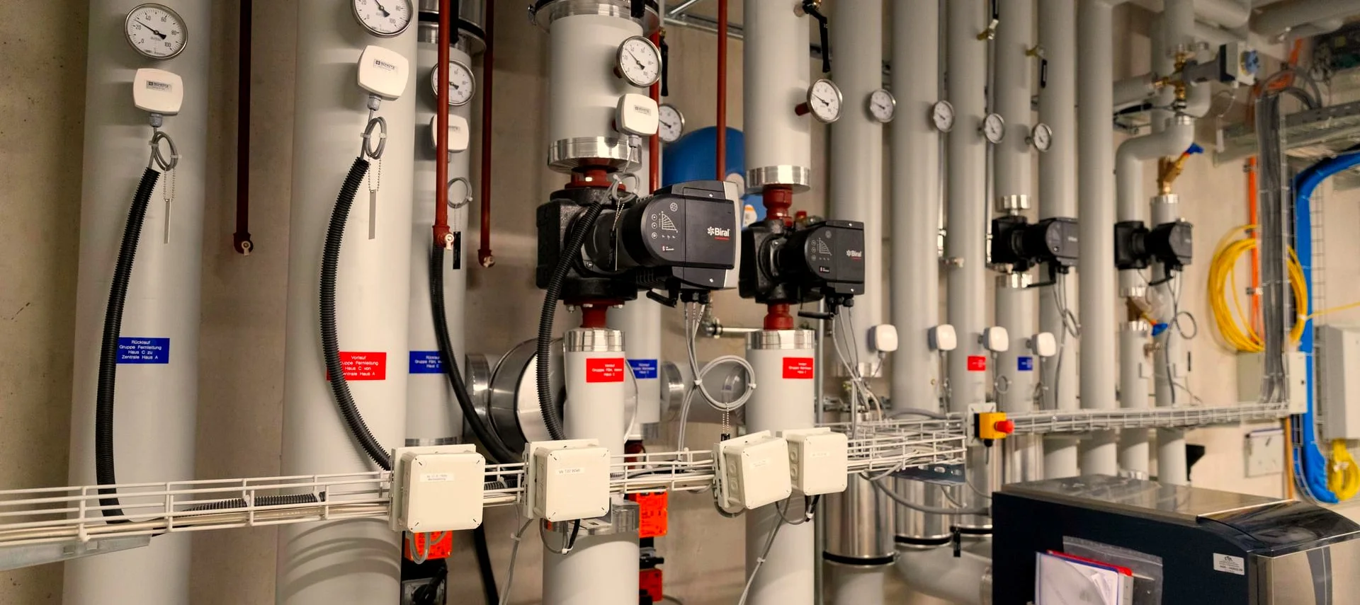 Technikraum mit Heizungsverteilung und Umwälzpumpen.