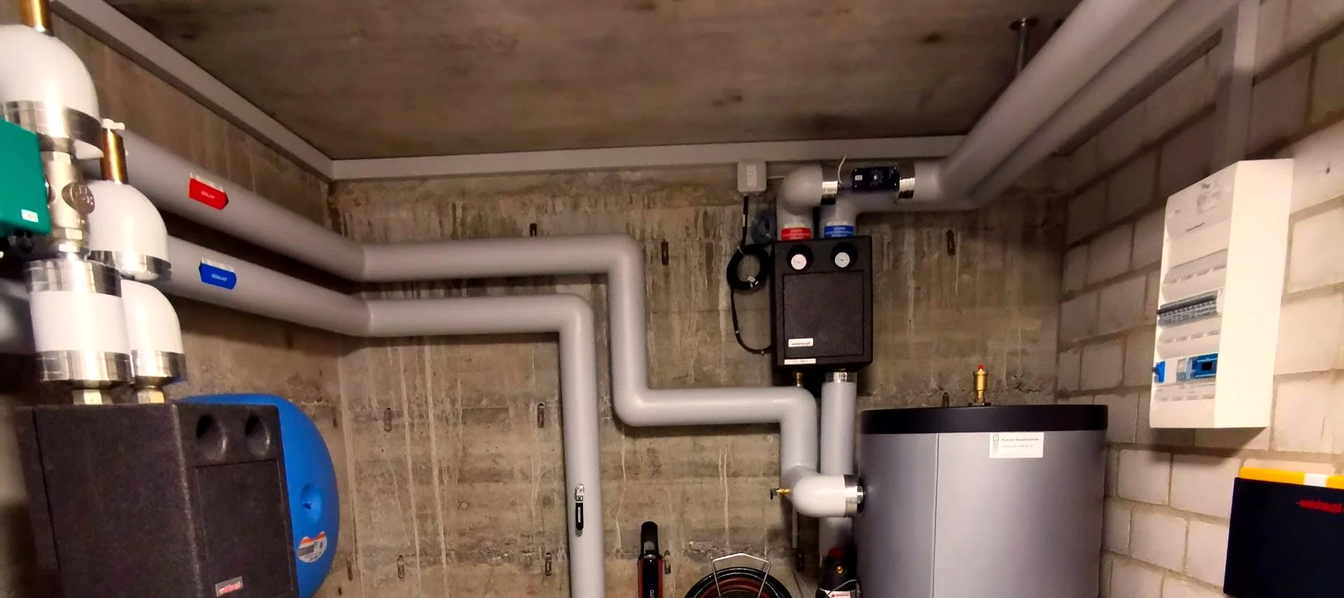 Heizungsanlage im Technikraum mit Speicherbehälter und Rohren.