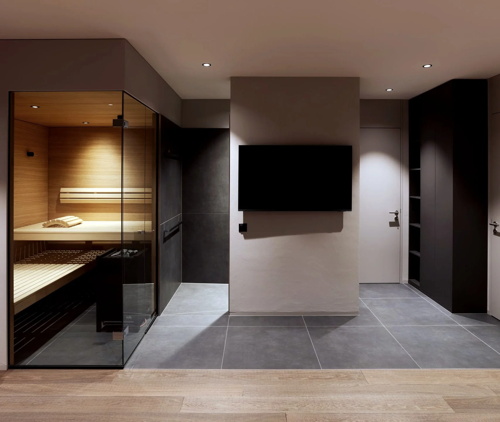Spa-Bereich mit verglaster Sauna und dunklen Einbauten.