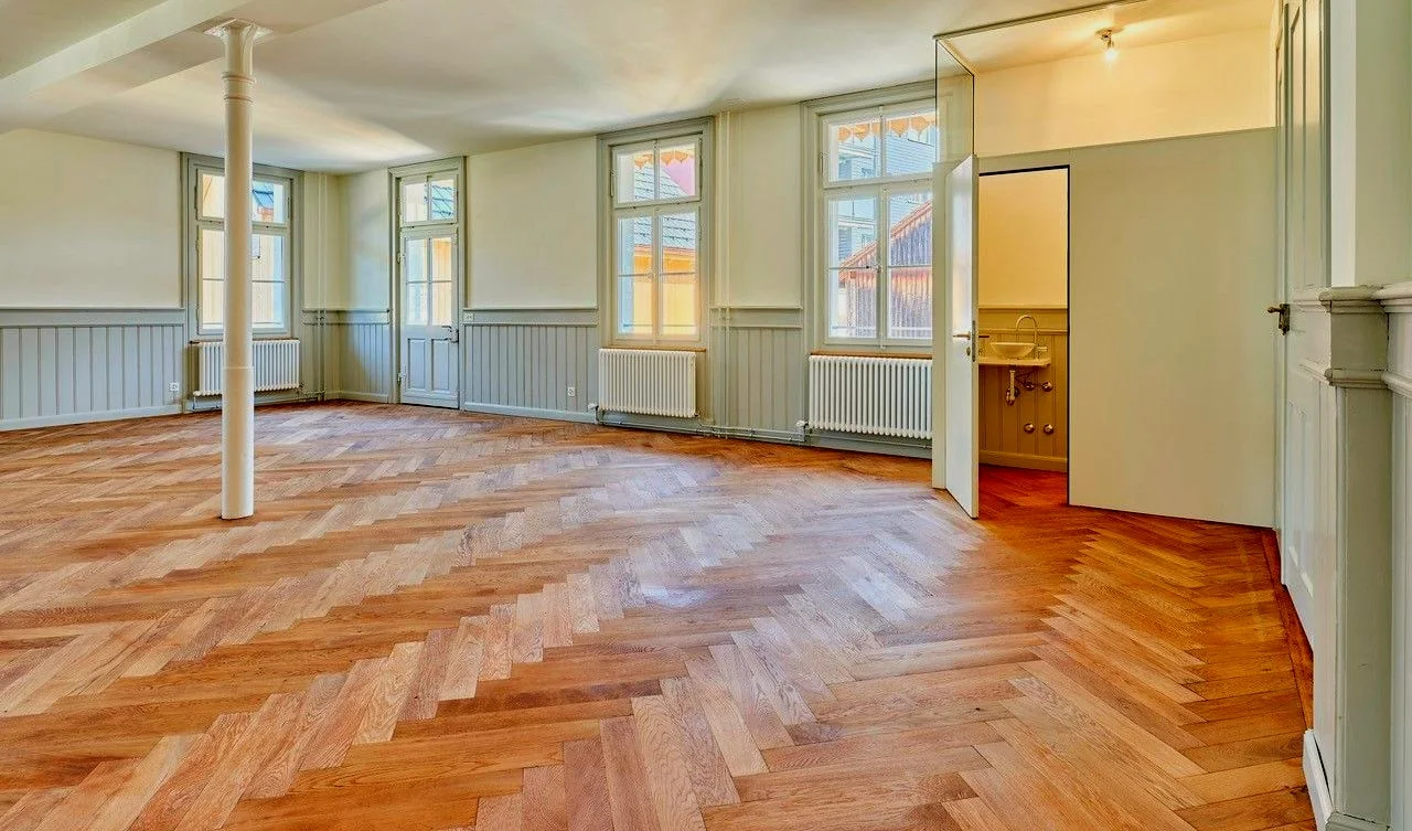Heller Raum mit Parkettboden und Säule.